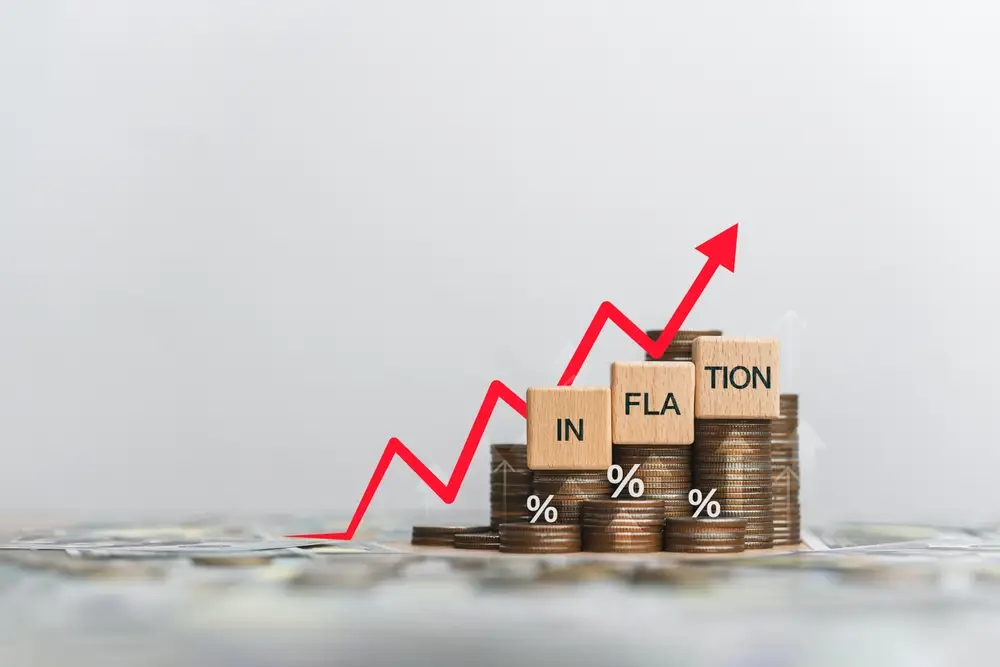 A red arrow climbing stairs made of coins with 'inflation' written on wooden blocks