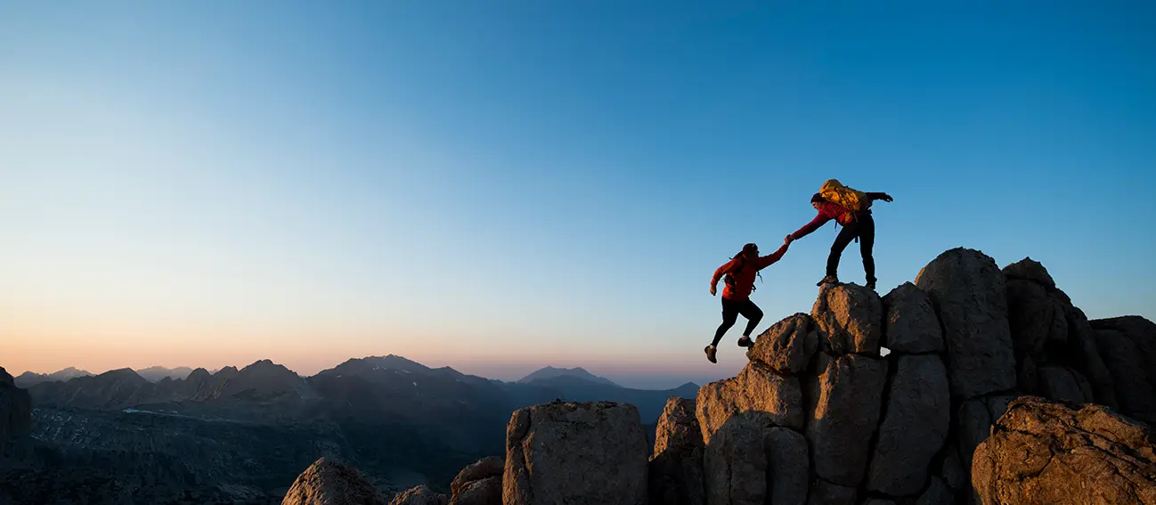 Two people climbing a large boulder